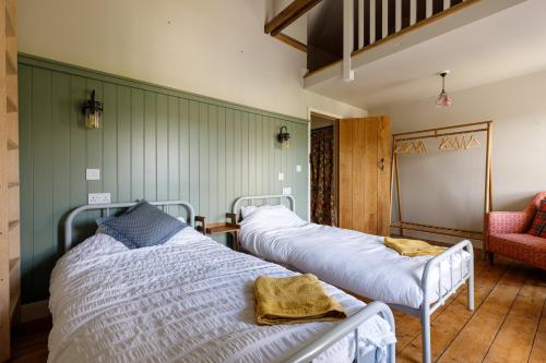 TanygrisiauCosy, 2-bedroom Snowdonia cottage mountain retreat的一间设有两张床和红色椅子的房间