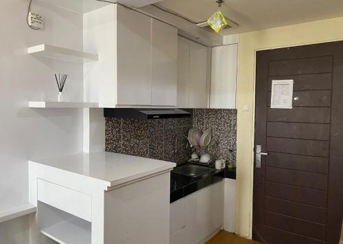 日惹Apartemen Malioboro city by Ameliarooms的厨房配有白色橱柜和黑色水槽
