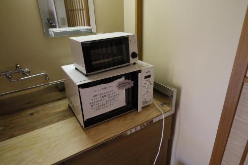 Isawa貸切温泉風呂付 ゲストハウス璃洛-りらく- 石和温泉 日本式宿 健康朝食付的微波炉,放在柜台上的盒子上