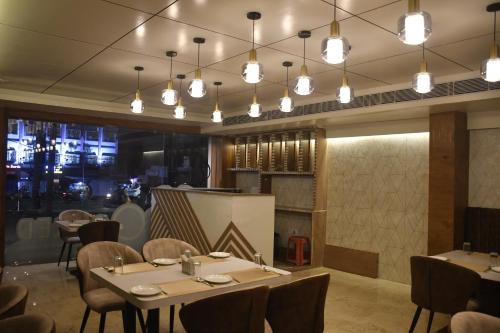 ĀsansolHOTEL EDEN GARDEN的用餐室配有桌椅和灯光