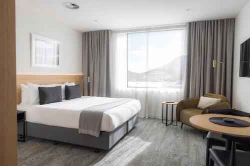芒格努伊山Quest Mt Maunganui的酒店客房配有一张床、一张桌子和一把椅子。