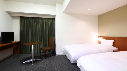 松本多美迎松本酒店的酒店客房设有两张床、一张桌子和一台电视。
