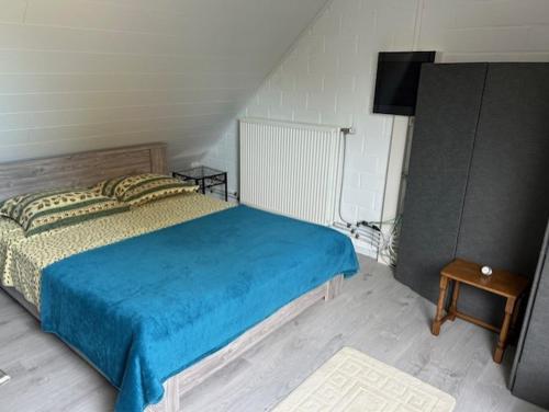 HerzeleDuivenboshuisje的一间卧室配有一张带蓝毯的床和一台电视