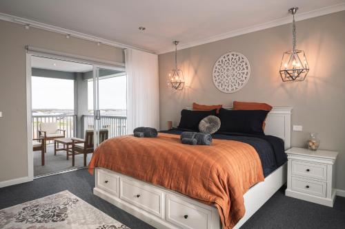 托基Hamptons in Torquay - 5 bath, Pool, Spa & Theatre!的一间卧室配有一张带橙色毯子的床和一个阳台