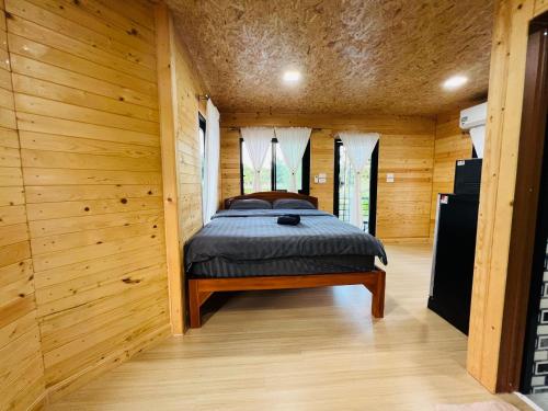 Ban Madua ChumphonBaanSuan Marigold บ้านสวนมาลีโกลด์的木制客房内的一间卧室,配有一张床