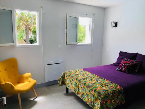 比亚里茨Villa Bella à 250m des plages的一间卧室配有一张床和一把椅子,还有两个窗户