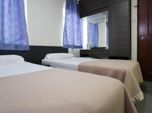 新加坡Amrise Hotel, Check in at 10PM, Check out at 9AM的一间卧室设有两张床,窗户配有蓝色窗帘