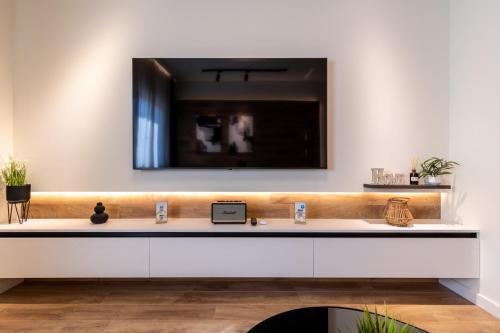 克桑西Good times - Luxury Studio Apartments的一间带水槽的浴室和墙上的电视