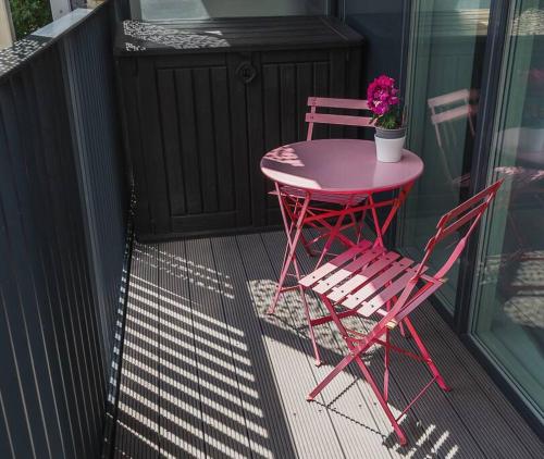 伦敦Cool Dalston studio with balcony and gym的阳台配有粉红色的桌子和两把椅子