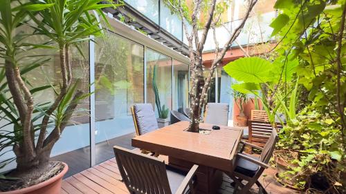 巴塞罗那ArtlifeBCN Urban Oasis Apartment的种有植物的庭院里摆放着木桌和椅子