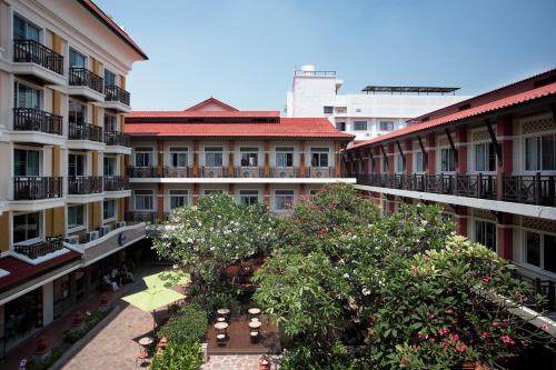 曼谷Rambuttri Village Plaza - SHA Extra Plus的公寓大楼设有种有树木和建筑的庭院。
