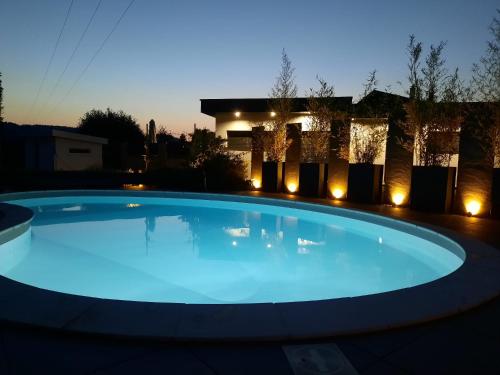 勒蒂约GITE DE LA PIERRE PLATE的夜晚在房子前面有一个蓝色的大游泳池