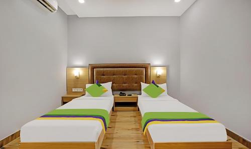 孟买ZARA GRAND HOTEL的配有白色墙壁和木地板的客房内的两张床