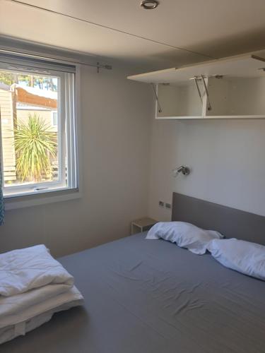 旺代蒙塔利韦Mobil Home Comfort XL 6 Personnes Montalivet的一间卧室设有两张床和窗户。