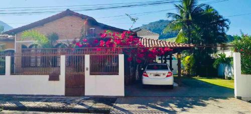 曼加拉蒂巴Casa em mangaratiba的停在一座鲜花盛开的房子前面的汽车
