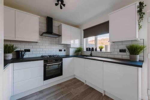 格拉斯哥SleepLuxury ApartHOUSE的厨房配有白色橱柜和炉灶烤箱。