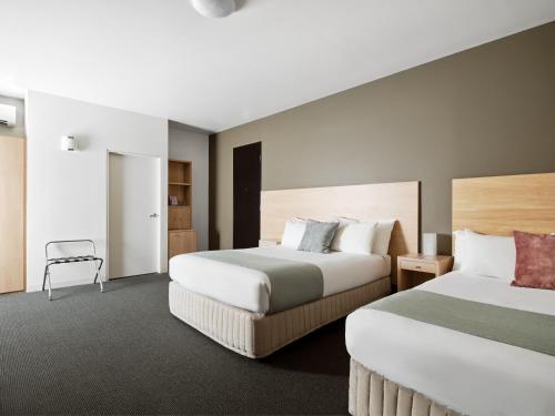 墨尔本Saint Kilda Beach Hotel - formerly Rydges St Kilda的酒店客房,配有两张床和椅子