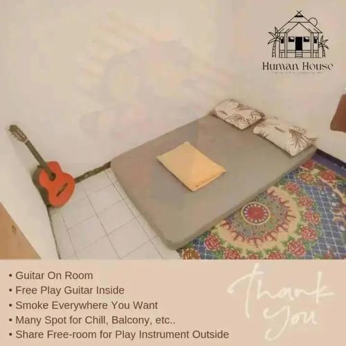 泗水Human House的一间位于地板上并配有桌子和吉他的房间