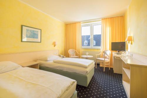 哥廷根Trip Inn Hotel Astoria的酒店客房设有两张床和电视。