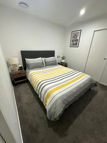 奥克兰Trafalgar Place的一间卧室配有一张带条纹毯子的大床