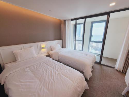 釜山Best Travel in Haeundae with best location的酒店客房设有两张床和窗户。