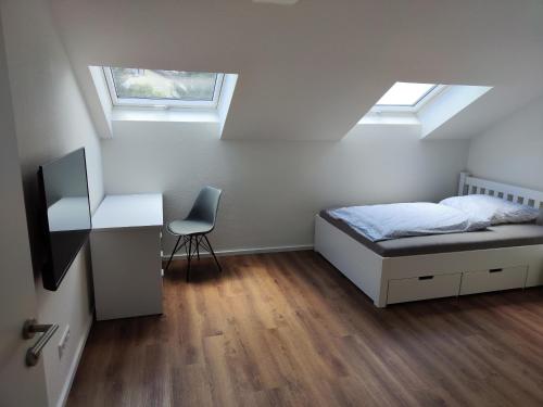 普福尔茨海姆Apartmenthaus Pforzheim的一间卧室配有一张床、一张书桌和两个窗户。