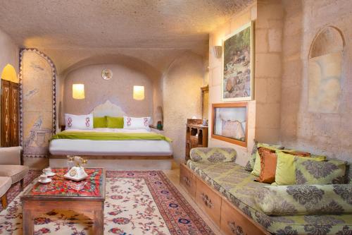 AyvalıCappadocia Gamirasu Cave Hotel的一间卧室配有一张床、一张沙发和一张桌子