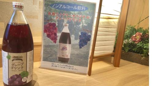 松江市Onyado Nono Matsue Natural Hot Spring的葡萄标志旁的一瓶葡萄酒