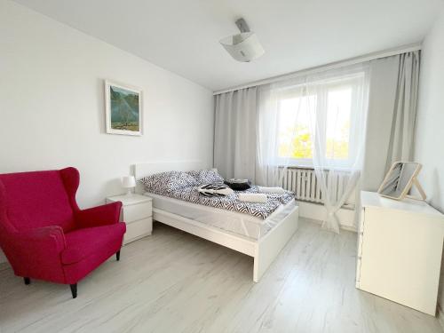 格丁尼亚19 Gdynia Centrum - Apartament Mieszkanie dla 8 os的一间卧室配有一张床和一张红色椅子