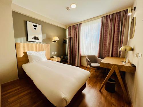 布鲁塞尔Bedford Hotel & Congress Centre Brussels的酒店客房设有一张大床和一张书桌。