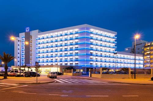 滨海罗克塔斯萨比纳尔最佳酒店的一座蓝色的大建筑,汽车停在停车场