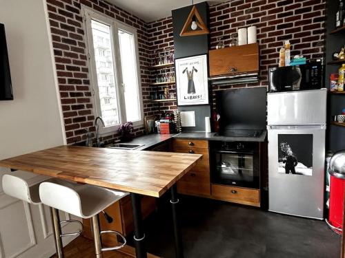 布洛涅-比扬古Appartement Confortable et Spacieux Boulogne-Billancourt的厨房配有木桌和砖墙