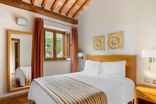 索里亚诺内尔奇米诺Palazzo Catalani Resort的卧室配有白色的床和镜子