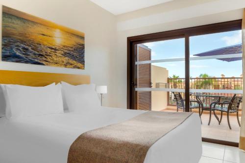 阿德耶皇家日落海滩俱乐部钻石度假公寓的一间卧室配有一张床,阳台配有桌子