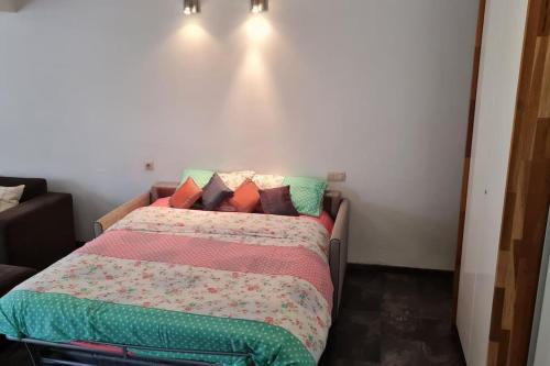 安特卫普Lux & Cozy Apt + Garden +Jaccuzi的一间卧室配有一张带色彩缤纷的毯子和枕头的床。