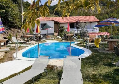 MemaliajVila Sofia Gllava - Resort的庭院内的游泳池,配有椅子和遮阳伞