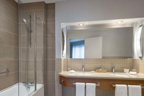 沃尔瑟姆阿比Delta Hotels by Marriott Waltham Abbey的浴室设有2个盥洗盆、淋浴和镜子。