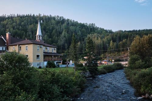 Riviere EterniteAUBERGE DU DIMANCHE - Hotel - Fjord-du-Saguenay - l'Anse-Saint-Jean - Riviere-Eternite的教堂和建筑物前的河流