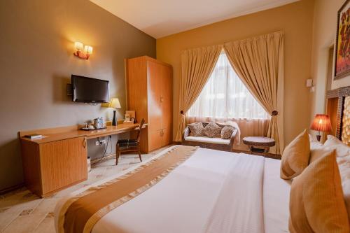 达累斯萨拉姆The Amariah Hotel & Apartments Mikocheni的酒店客房设有一张大床和一张书桌。