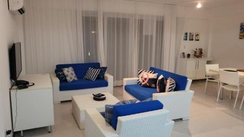 Entre RiosApartamento Particular de 03 suítes, Resort Treebies, Praia de Subauma - Ba的客厅配有蓝色和白色的椅子和桌子