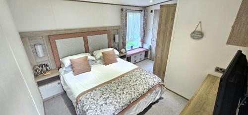 圣奥斯特尔Hot Tub Lodge Cornwall - Meadow Lakes Holiday Park的一间卧室配有一张大床和电视