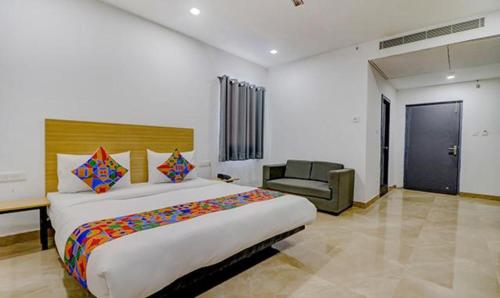 瓦拉纳西FabHotel Premium Kashi的一间卧室配有一张大床和一把椅子