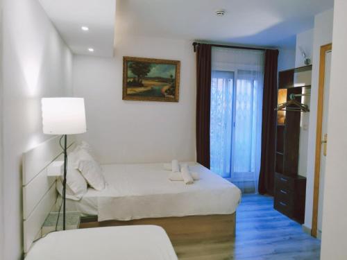 巴达洛纳Barcelona CoronaHostal的白色卧室配有床和灯