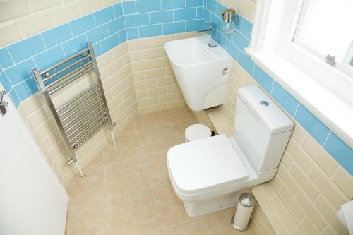 伦敦库克船长宾馆的浴室设有白色卫生间和蓝色瓷砖墙。