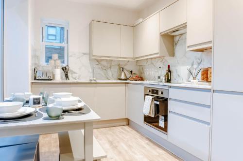 哈罗盖特Mayfield - Central Harrogate Apartment - Ground Floor的白色的厨房配有白色的橱柜和桌子