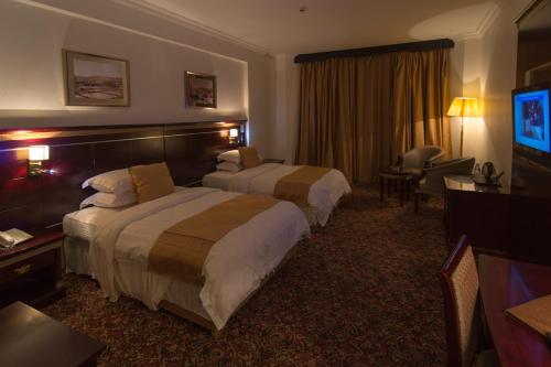 艾卜哈Shafa Abha Hotel的酒店客房设有两张床和一台平面电视。