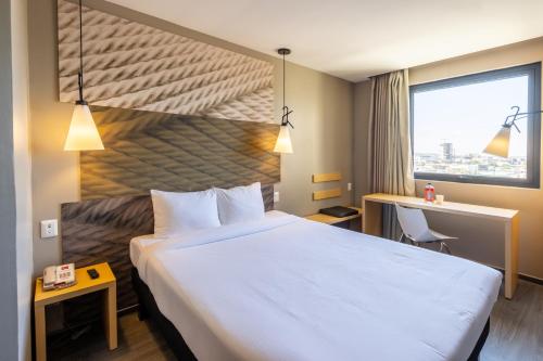 提华纳ibis Tijuana的一间设有大床和窗户的酒店客房