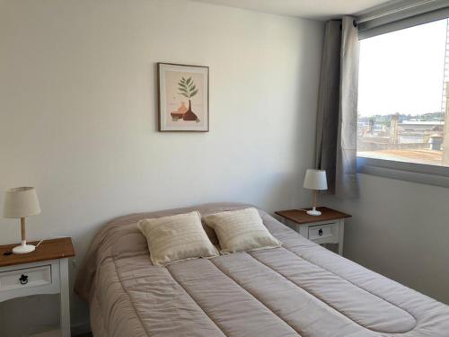 梅塞德斯Apartamento céntrico en Mercedes Uruguay的卧室内的一张床位,设有两个床头柜和一扇窗户