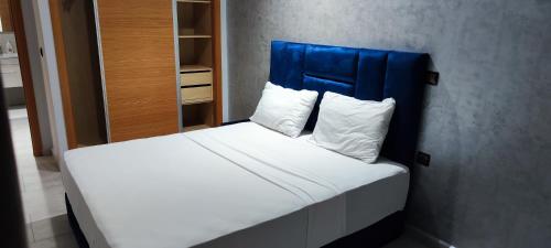 丹吉尔Les Belles Appartements Family Only的一张带蓝色床头板和白色枕头的床