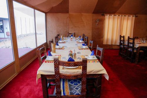 梅尔祖卡Luxury berber style的一间带桌椅的用餐室和大窗户